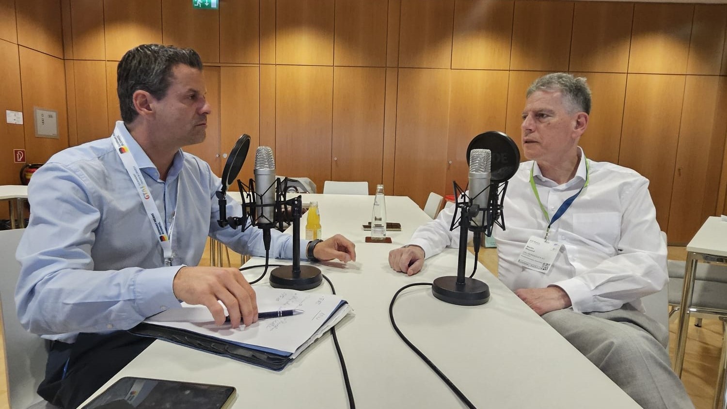 Dr. Arnt Baer von der GELSENWASSER AG sitzt links, Martin Weyand vom BDEW rechts, an einem Tisch, dazwischen das Mikrofon für die podcast-Aufnahme in einem ruhigen Raum während der IFAT 2026 in München.