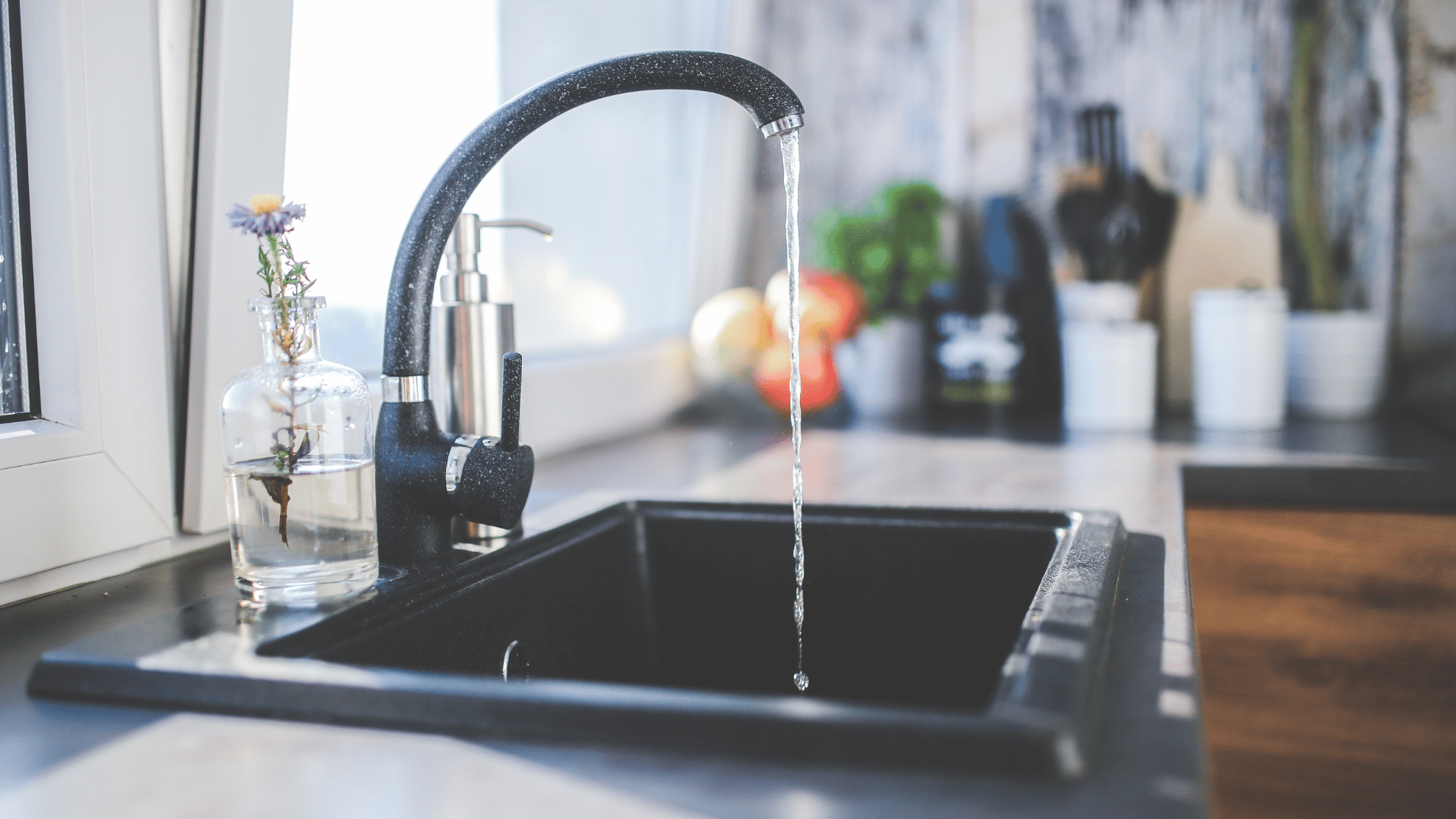 Ein schwarzer Wasserhahn in der Küche, aus dem das Wasser läuft.