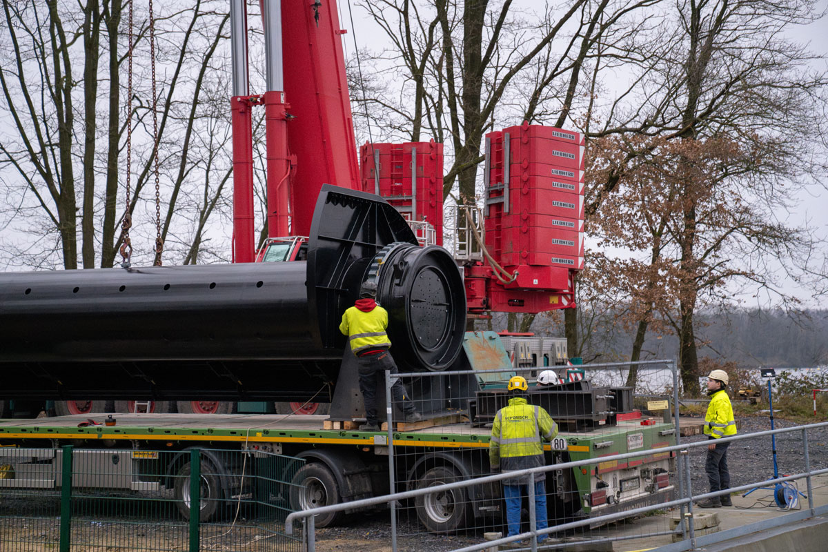 Hier wird die erste der beiden neuen Stahlwalzen per Schwertransporter angeliefert. Um die Walze vom Transporter auf das Wehr zu haben, war ein 450-Tonnen-Kran notwendig. 
