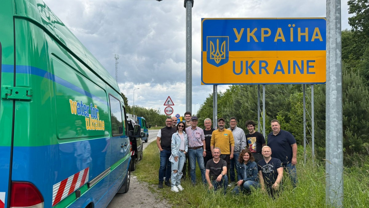 Alle Teilnehmenden des Konvoi 20 für Water4Ukraine vor dem Grenzschild zur Ukraine..